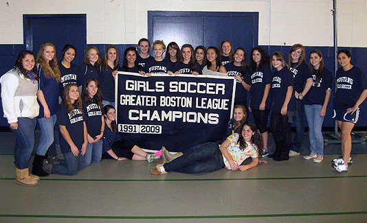 MHS varsity girls soccer team with GBL champs banner